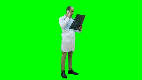 Doctor Holding Xray Results and Talking on the Phone on a Green Screen, Chroma Key.