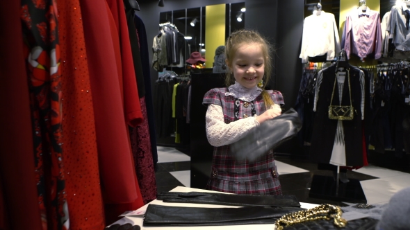 5 Years Old Girl Trying on Gloves in a Clothing Store.
