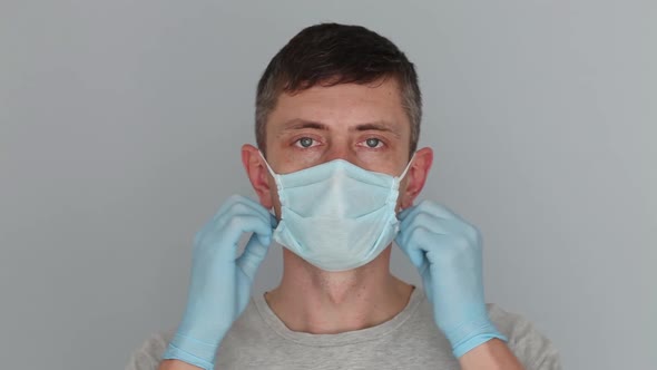 Young man takes off medical mask and smiling looking at camera.
