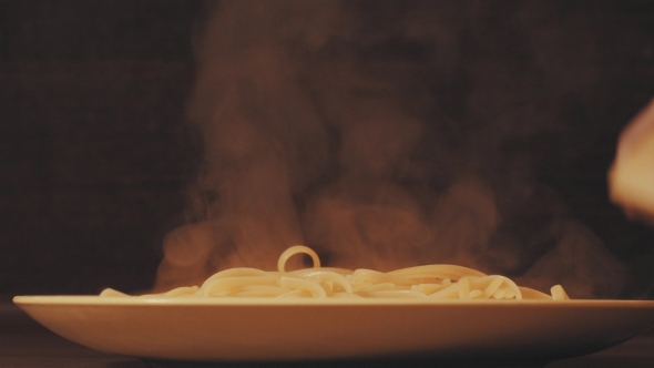 Hot Spaghetti Putting on a Plate, Sprinkling with Cheese and Adding Tomato Sause