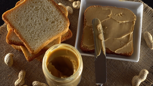 Tasty Peanut Butter Being Spread on White Toast