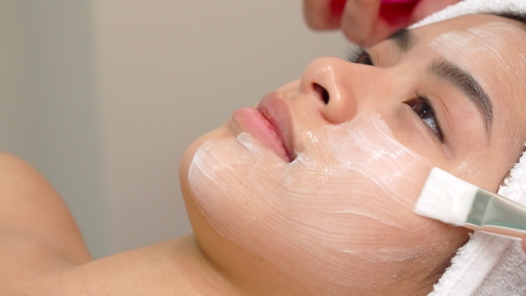Beauty Specialist Uses Brush To Apply Cosmetic Mask on Girl's Face alt