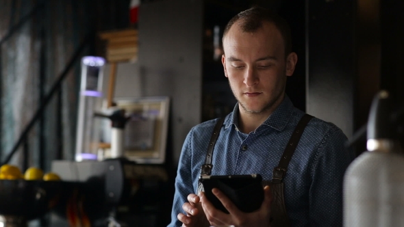 Young Bartender Exploring New Cocktails Using Tablet