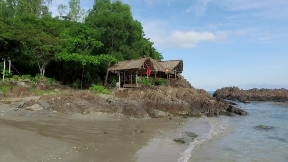 Sandy Beach With Rocks and Wooden Bungalow on a