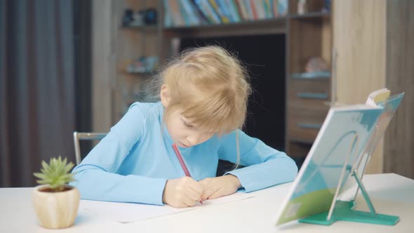 7 Year Old Girl Doing Homework with Textbooks alt