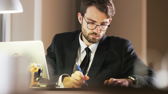 Young Businessman Writing and Thinking Deeply alt