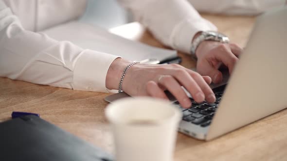 Closeup View of Young Businessman Is Typing During Working Day at Table in Modern Office.