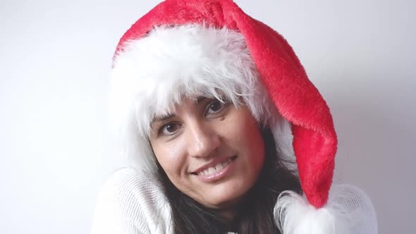 Woman in santa claus christmas hat smiling and looking at the camera on a white background close-up