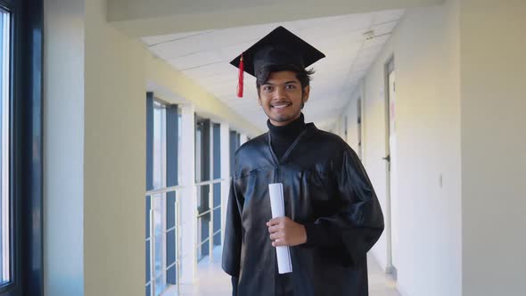 Indian Graduate in Mantle Stands with a Diploma in Her Hands and Smiles alt