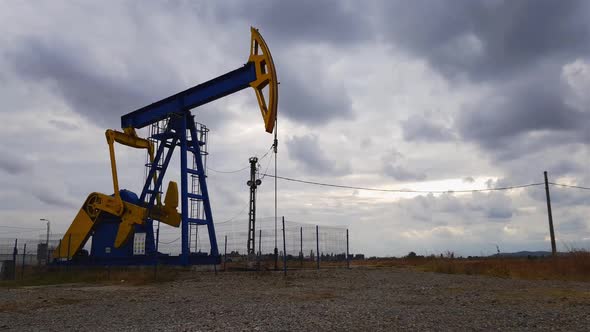 Oil well pumpjack operating frantically, stormy sky time lapse, Ploiesti Romania alt
