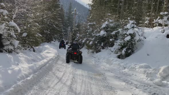 Driving an Quad Bike on a Snowy Forest Road alt