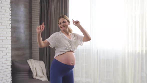 A Woman with a Big Tummy and a Baby Inside a Happy Pregnant Woman Dancing at Home to Music
