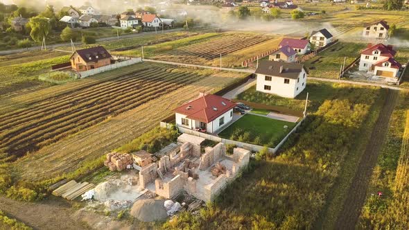 Top down aerial view of two private houses, one under construction with wooden roofing frame  alt