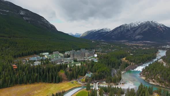 Aerial footage of massive hotel at the foot of the mountains near Bow River (Banff, Alberta, Canada) alt