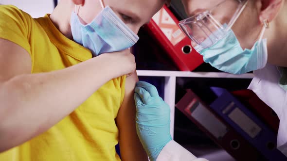 Medical nurse wearing protective gloves and a mask gives an injection to a patient in a hospital. alt