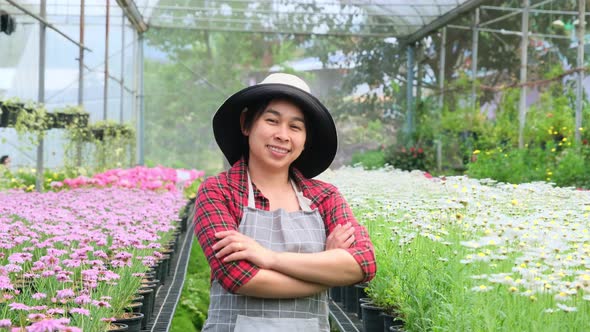 Smiling gardener with her arms crossed and looking at the camera in the greenhouse. alt