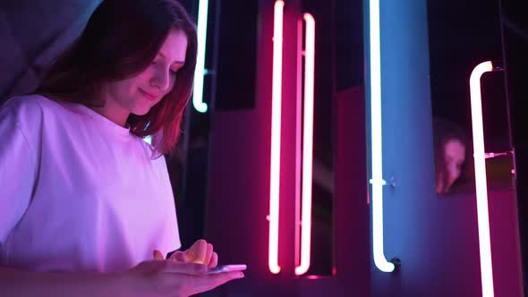 Online Chatting in the Phone Against the Background of Neon Lamps alt