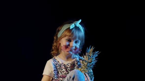 Stylish Cute Teenager Kid Girl Hiding Behind Pineapple on Black Background Smiling Fooling Around alt