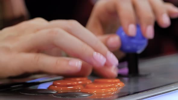 Woman Playing Retro Arcade Machine Game and Pushing Orange Buttons  Close Up
