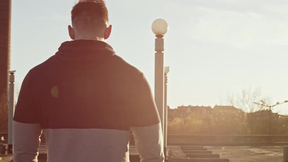 Young and fit man having evening workout outdoor. Urban sunset background. alt