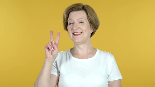 Victory Sign By Old Woman Isolated on Yellow Background alt