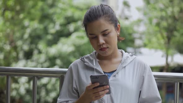 Portrait beautiful young Asian woman fitness runner using mobile phone.