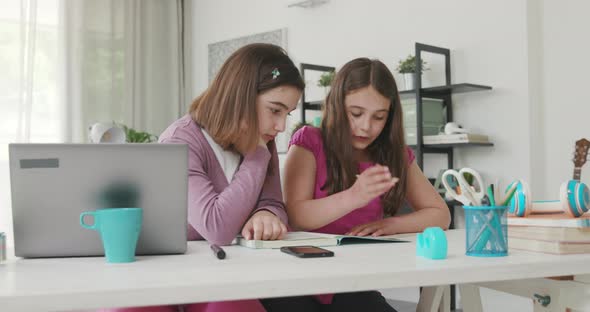 Girl helping her younger sister with her homework, they are studying together