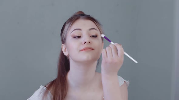 Woman Makes Eyelid Makeup Looking in the Mirror Happy Beautiful Lady Takes Care of Her Face