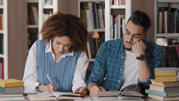Two Students Guy and Girl Sitting at Desk Classroom Writes Notes in Notebook Writing Information alt