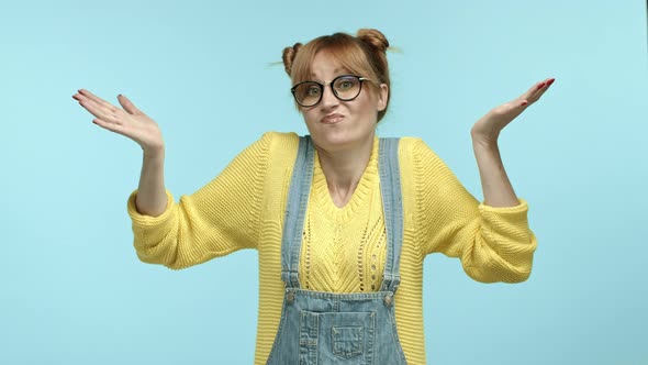 Cute Hipster Woman in Glasses and Overalls Raising Hands Up and Shrugging Shaking Head Confused Know