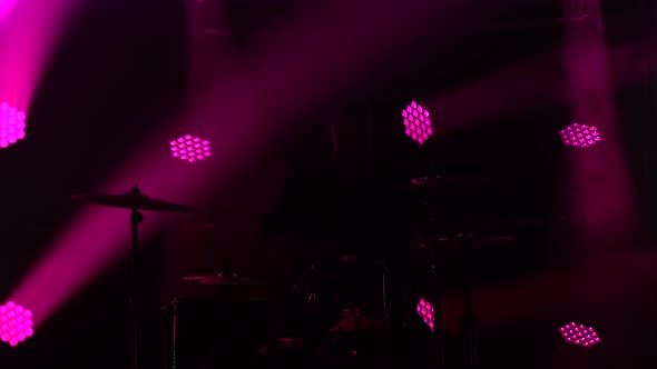 Silhouette Drummer Playing on Drum Kit on Stage in a Dark Studio with Smoke and Neon Lighting alt