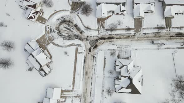 Top down aerial view over residential neighborhood after snowstorm. Sand swirls in the street.