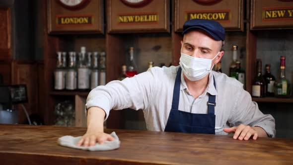 Young Man Waiter Barman or Worker in Cafe Restaurant Cleaning Barspraying Detergent or Sanitizer