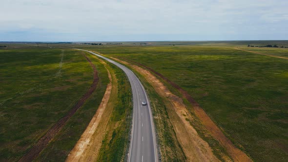 Car Moving Along Road Across Horizonless Plain in Russia