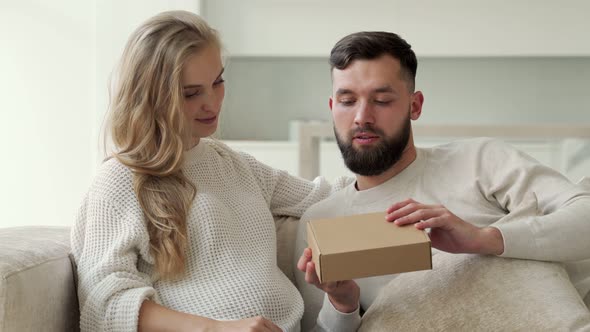 Bearded Husband Surprised His Pregnant Wife with a Gift Box and the Wife Opens the Gift Box and alt