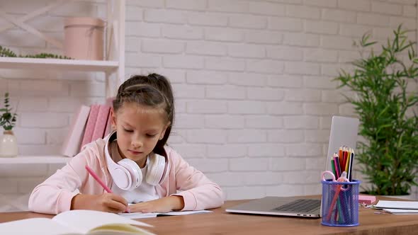 Little Child Girl Using Laptop for Doing School Tasks at Home and Writing Notes