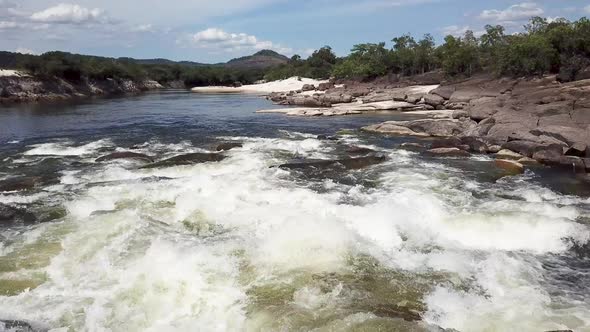 Low flying drone shot over fast flowing rapids on a tropical river in South America alt