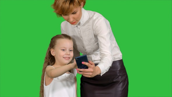 Young mother teaching her daughter how to use smartphone