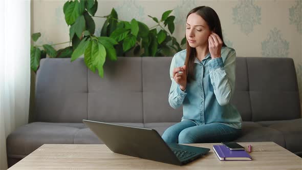 Woman Taking Wireless Headphones to Have Video Call alt