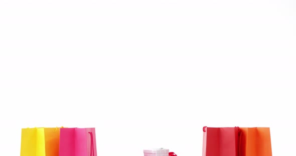 Multicolored shopping bags with wrapped gifts against white background alt