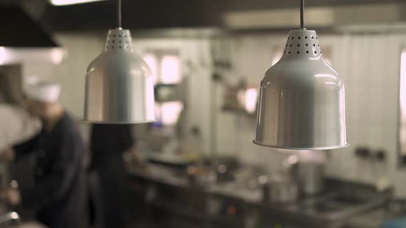 Close Up of Lamps in the Kitchen Restaurant with Chefs on Background alt