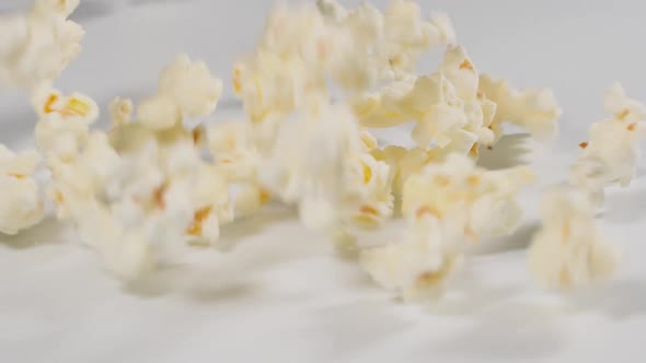 Fresh popcorn falling onto a white surface in slow motion alt