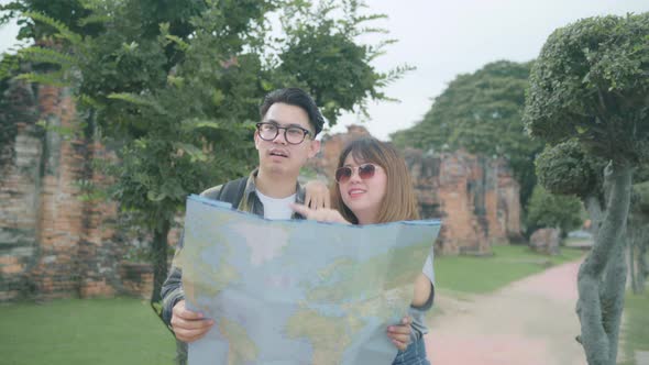 Asian couple direction and looking on location map while spend holiday trip at Ayutthaya Thailand alt