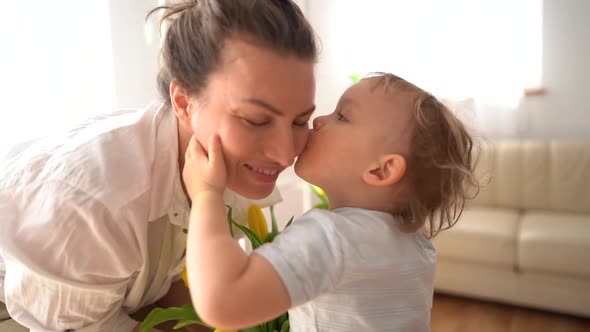 Close Portrait of a Little Cute Son Kissing His Mom Congratulating Her on March 8 or Mothers Day alt