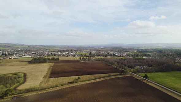 Aerial Drone flying towards Tractor Ploughing a field in Rural Perthshire, Scotland alt