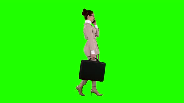 Business Lady with Cases in Hands Speaks on the Phone. Green Screen. Side View. Slow Motion alt