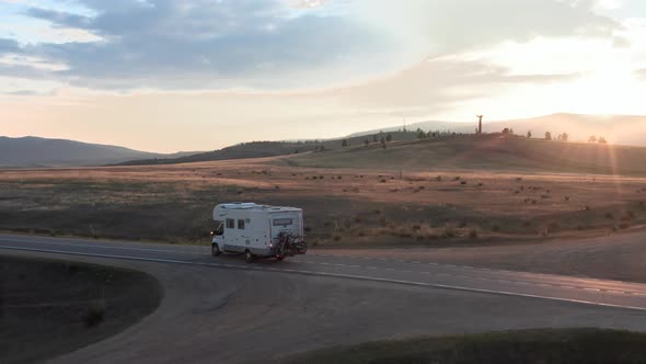 Drone Follows Camper Van Rv From the Back It Sunset on Road in Wilderness