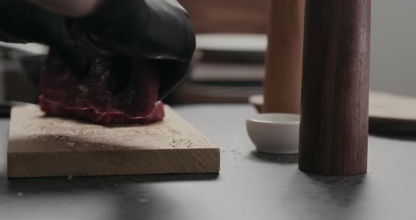 Slow Motion Orbit Shot of Man Rub Seasoning Into Raw Beef Steak on Oak Board alt