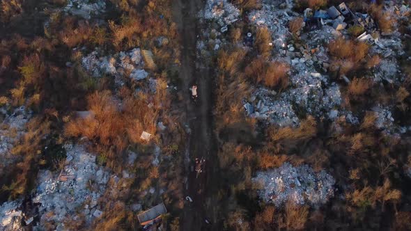 Aerial View of 2 Bikers Riding a Path Full of Waste Garbage Land Close to a City alt