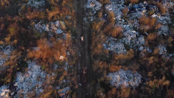 Aerial View of 2 Bikers Riding a Path Full of Waste Garbage Land Close to a City